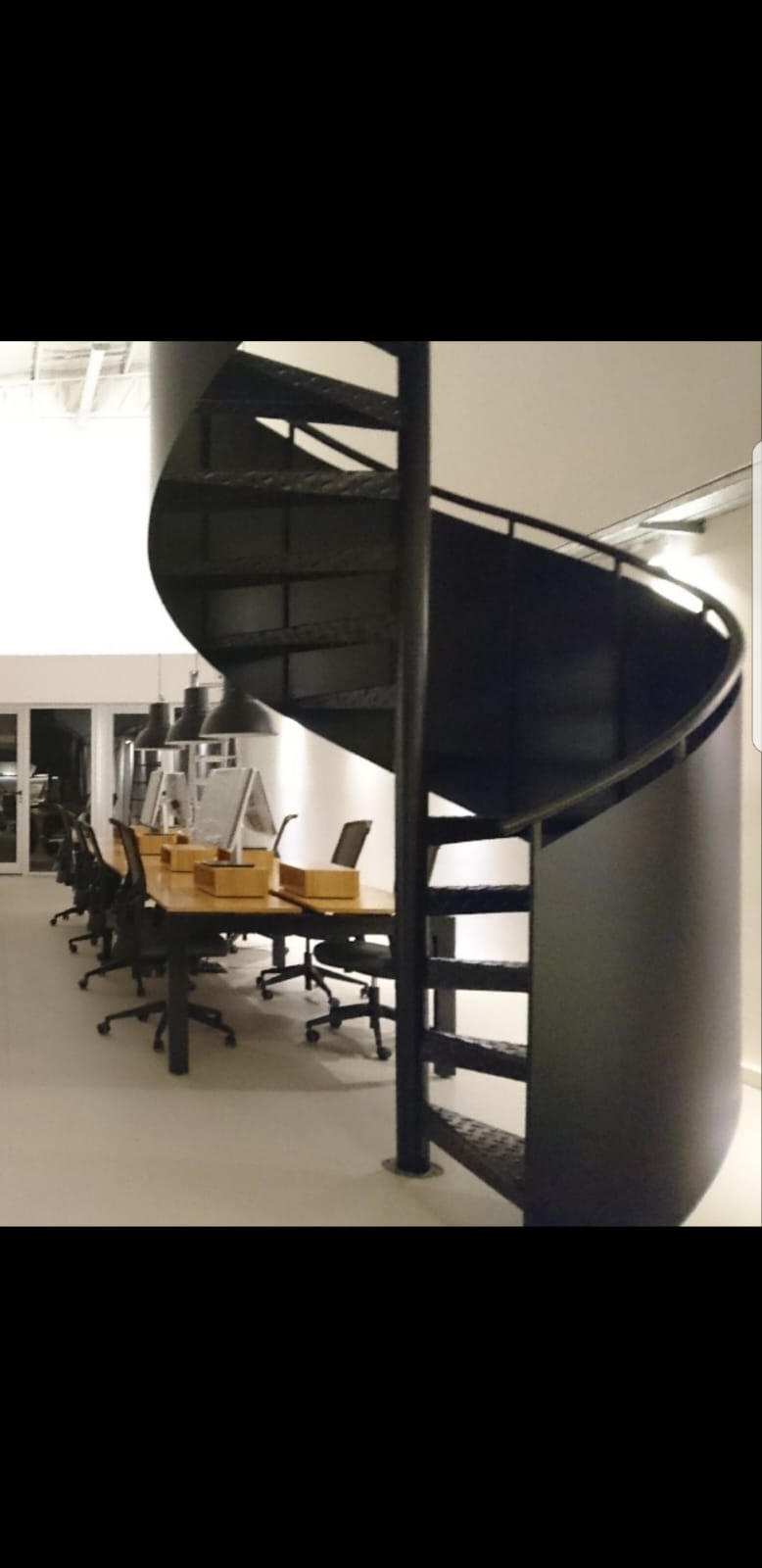 Escalera caracol negra en oficina de diseño moderno