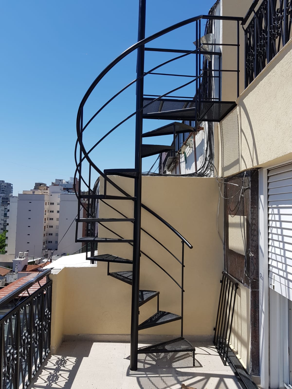 Escalera caracol negra exterior en balcón de edificio