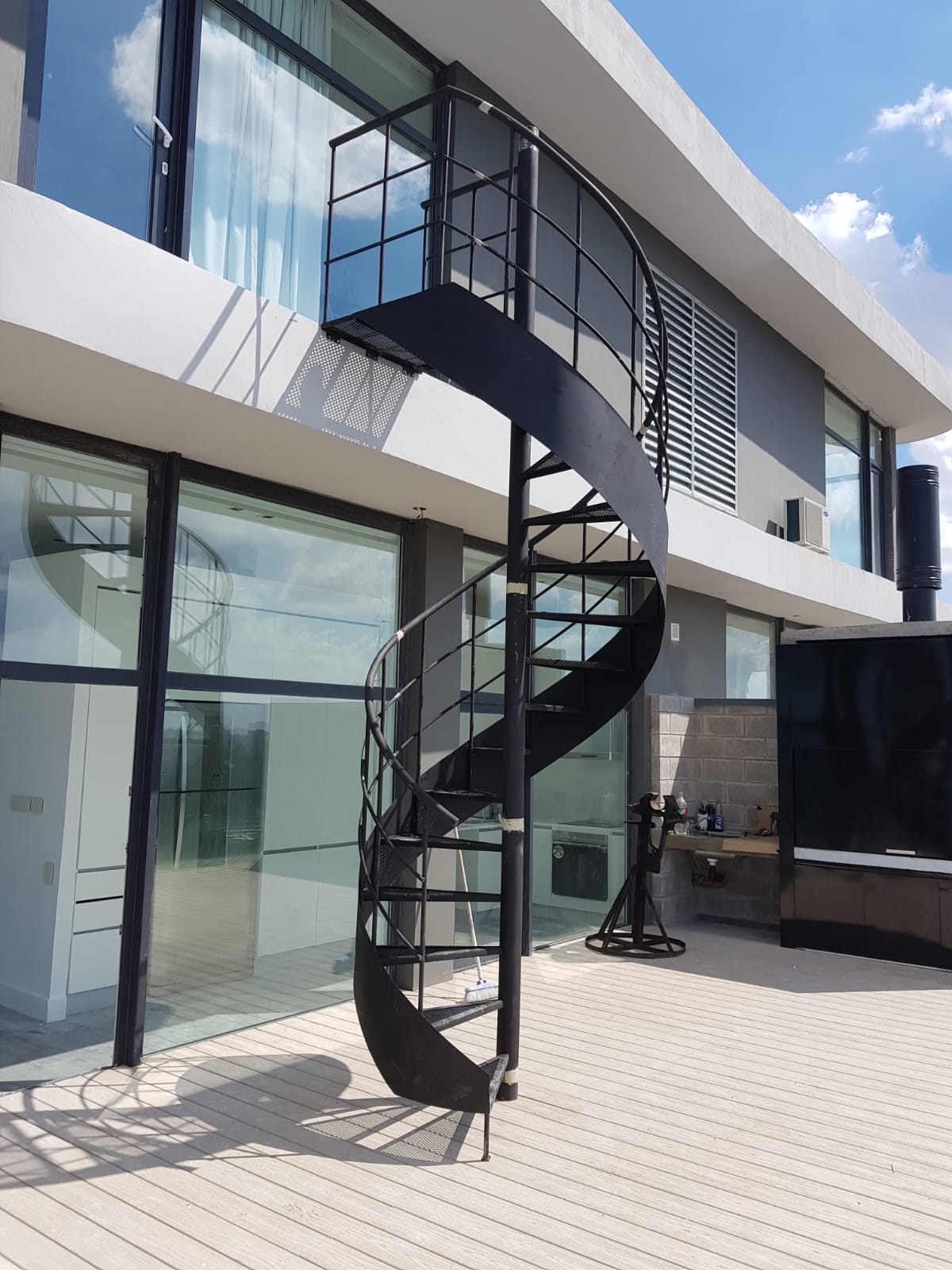 Escalera caracol negra exterior en deck de terraza moderna