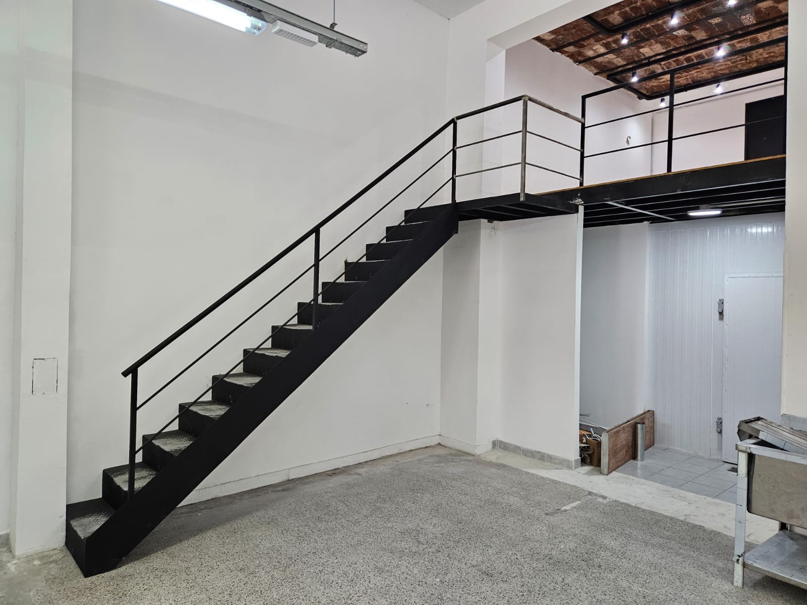 Escalera recta negra interior de entrepiso en galpón industrial