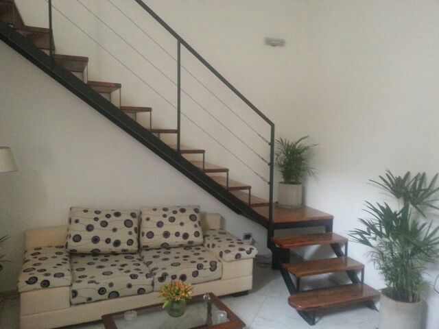 Escalera recta interior con baranda de cable y peldaños de madera oscura