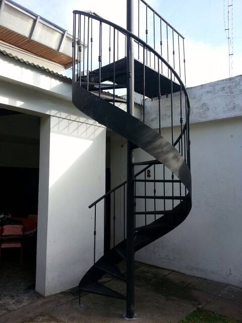 Escalera caracol negra exterior en galpón con techo de chapa