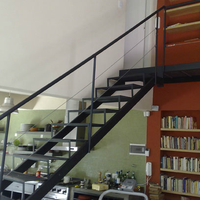 Escalera recta negra interior industrial con pasarela superior