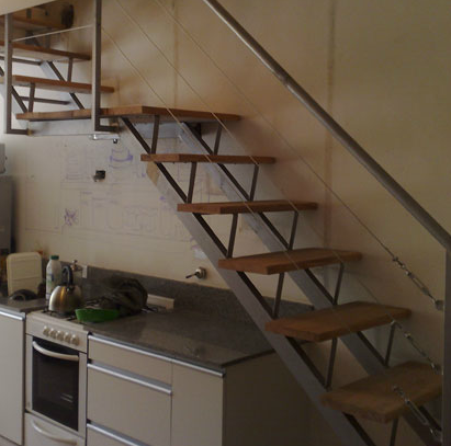 Escalera recta negra interior con baranda de cable y peldaños de madera clara