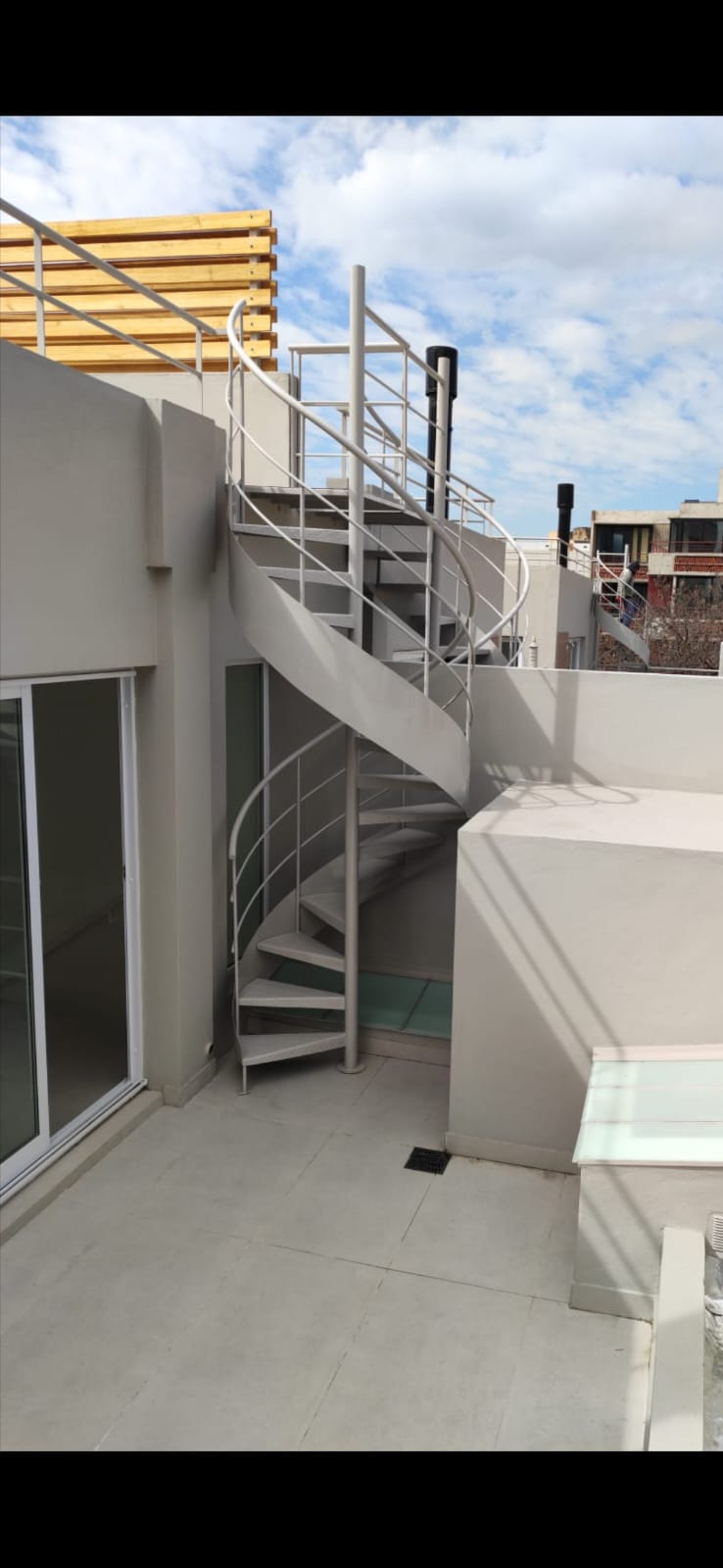 Escalera caracol blanca exterior en terraza con vista a la ciudad