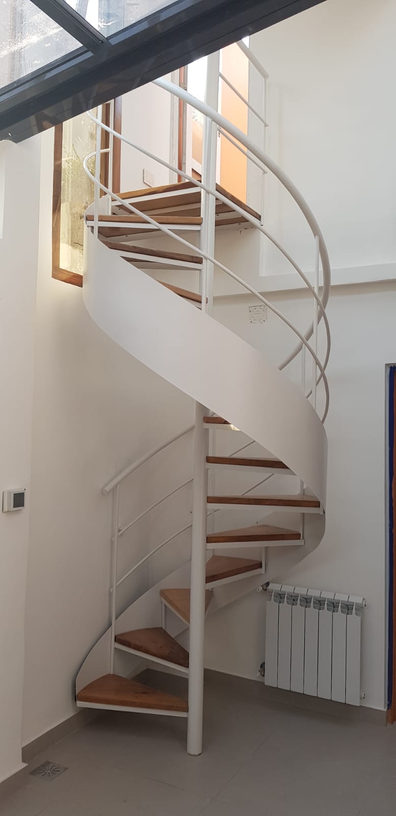 Escalera caracol blanca interior con peldaños de madera