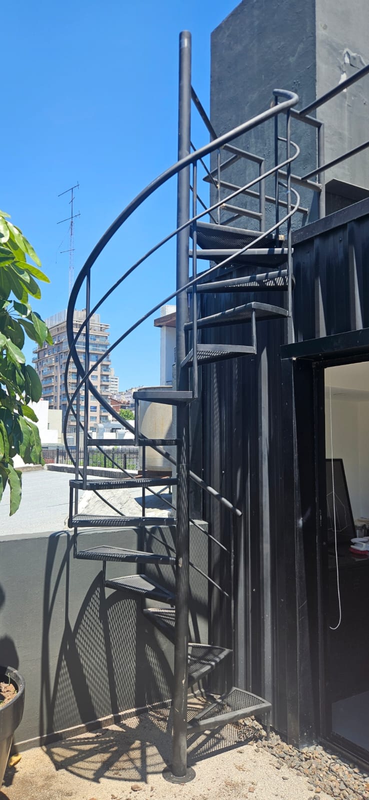 Escalera caracol negra en terraza exterior con vista a la ciudad, fabricada por Escafull