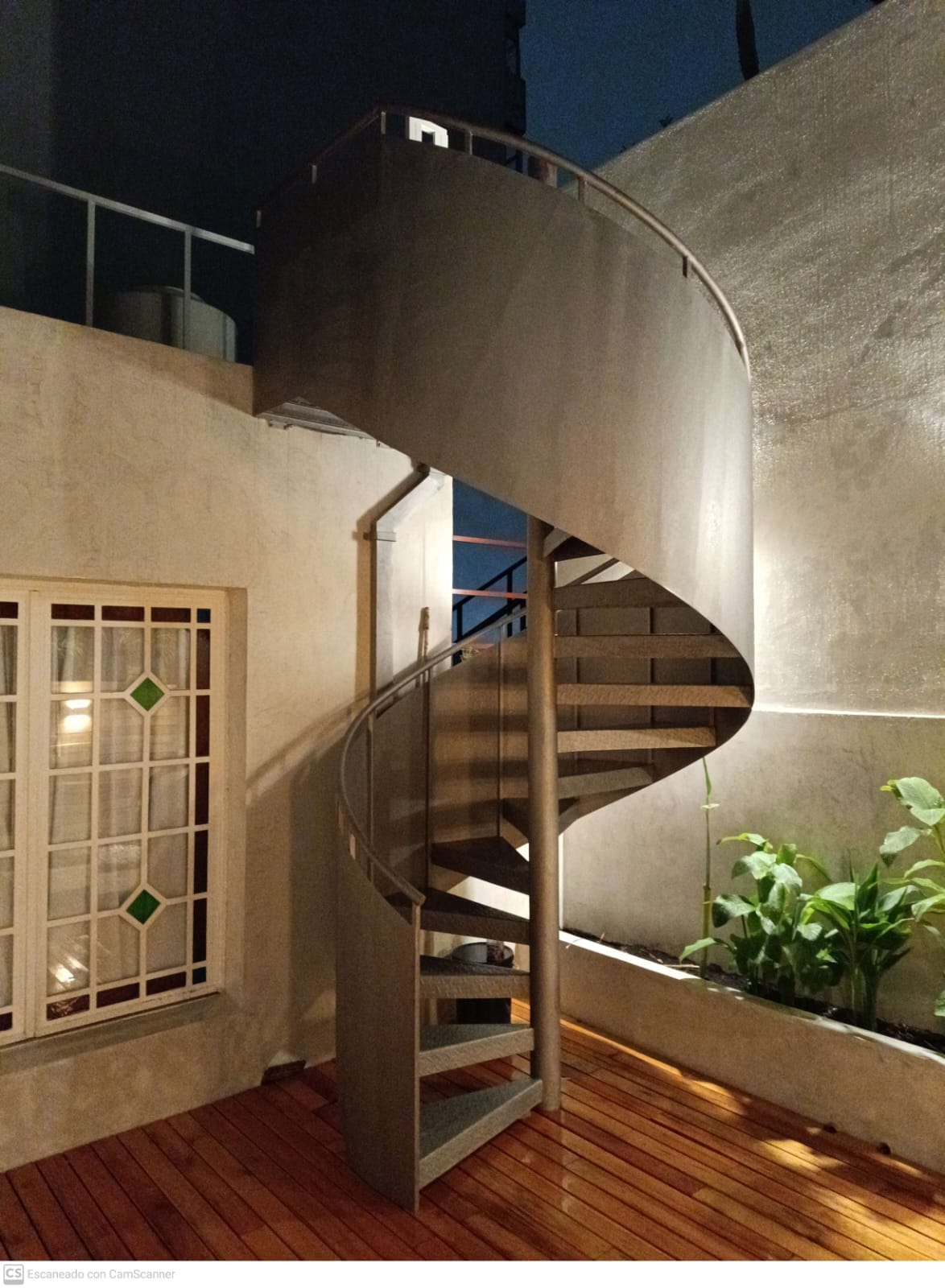 Escalera caracol exterior con peldaños de madera, vista nocturna