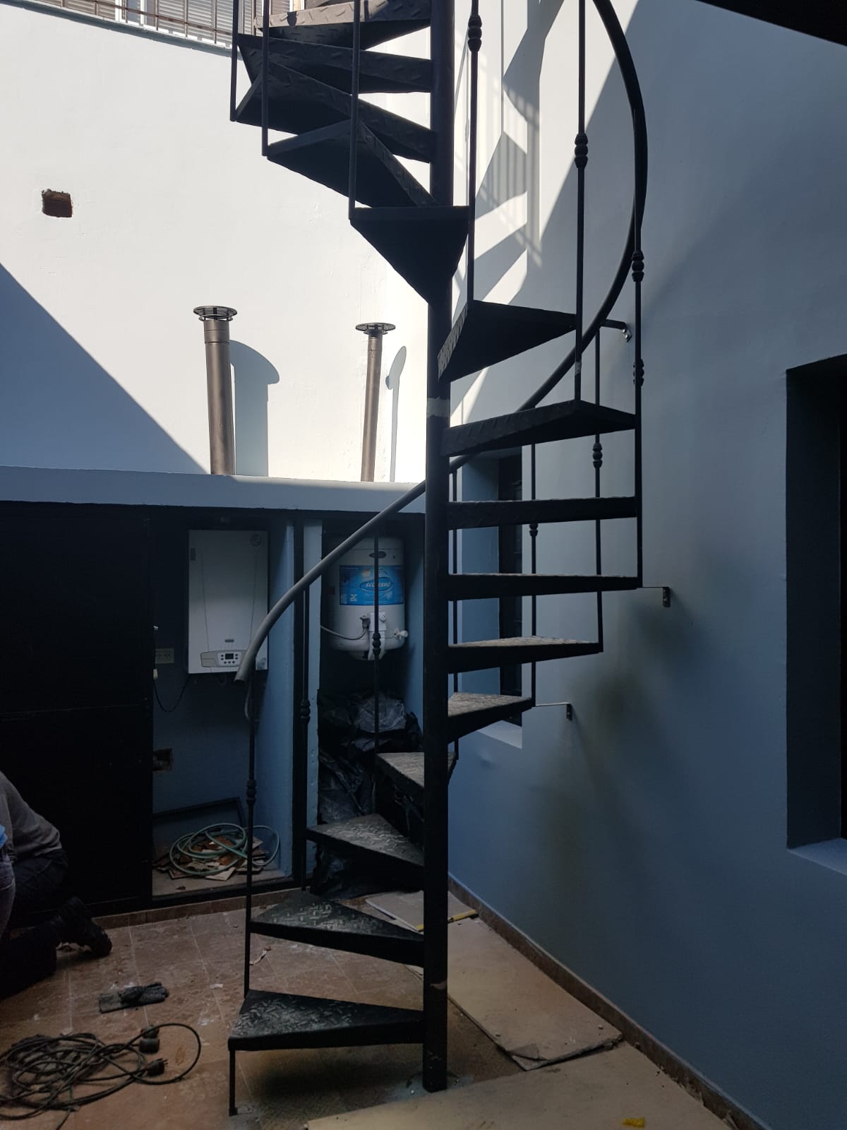 Escalera caracol negra interior, junto a espacio de termotanque