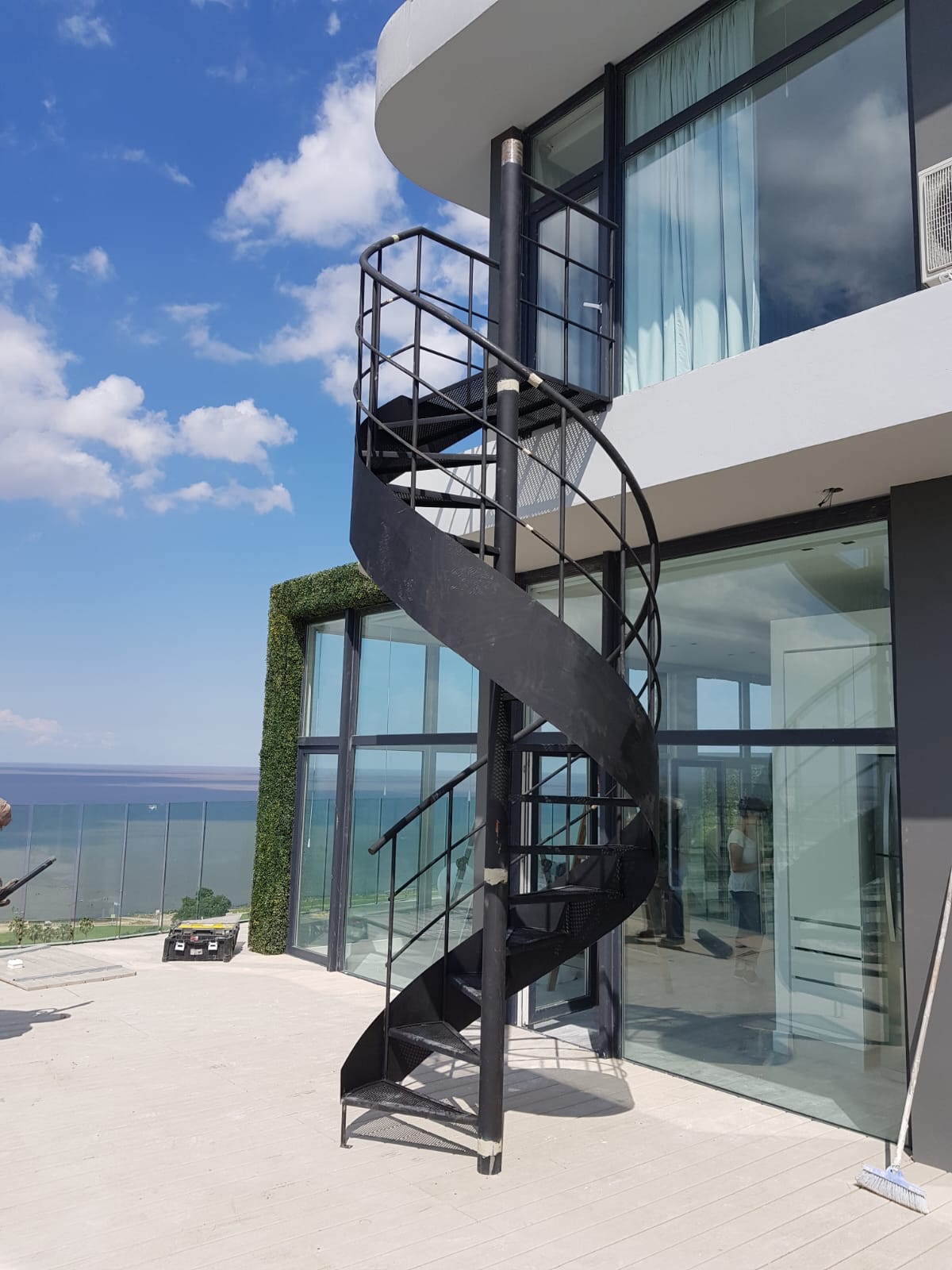 Escalera caracol de hierro fabricada por Escafull en fachada de vidrio frente al mar