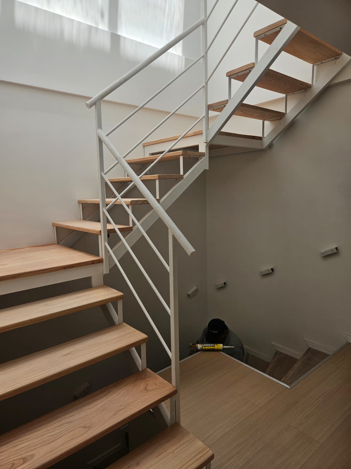 Escalera recta blanca interior con peldaños de madera, en obra
